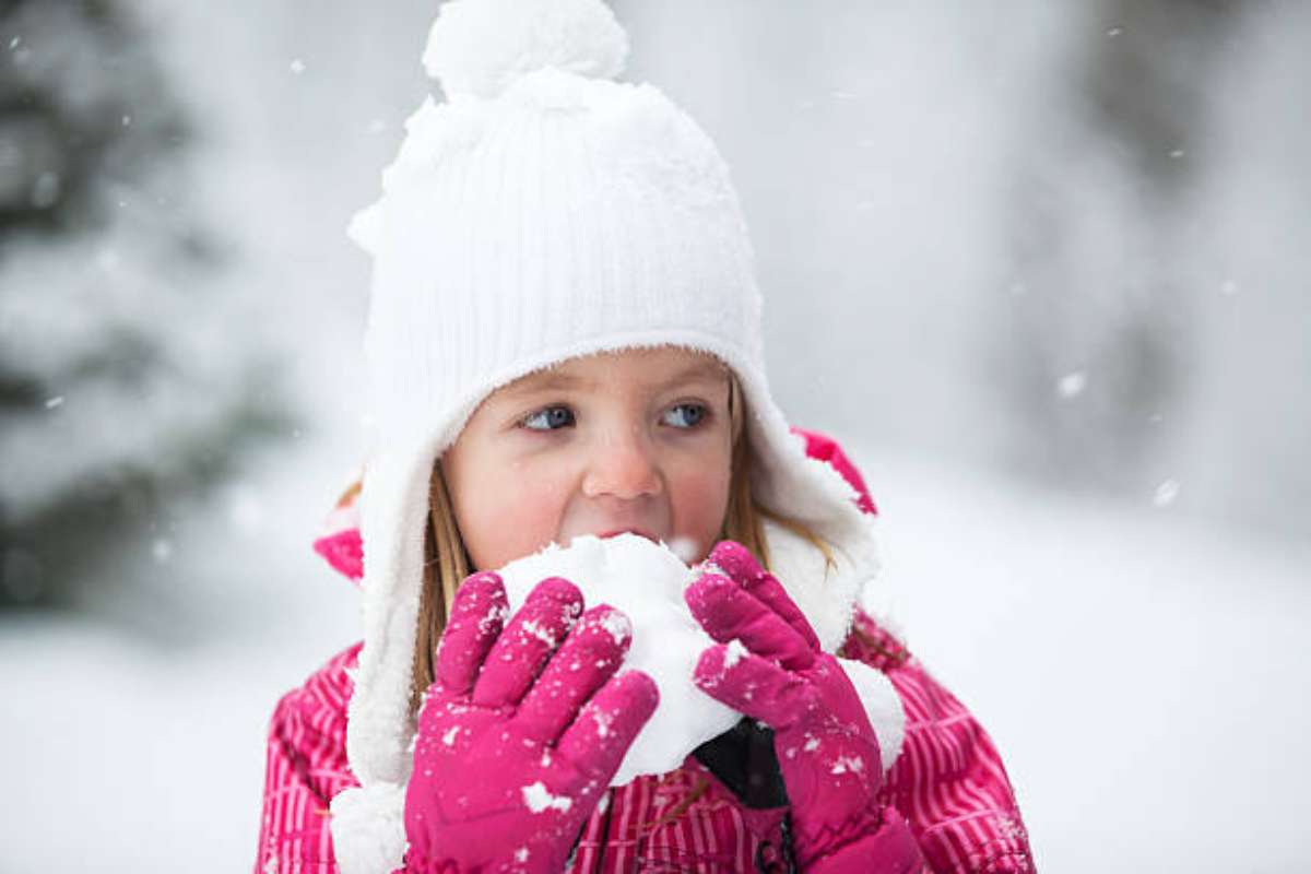 Bambina che mangia la neve