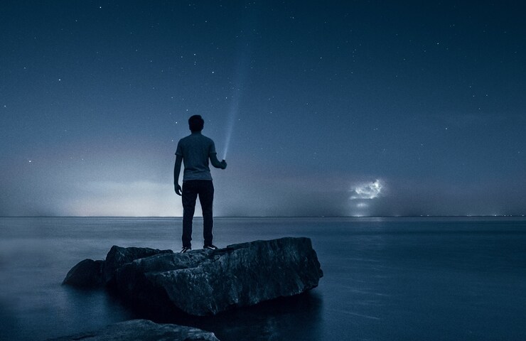 ragazzo guarda il cielo con una torcia