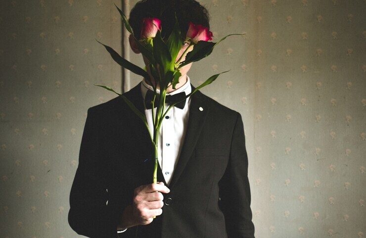 ragazzo che si copre il volto con delle rose